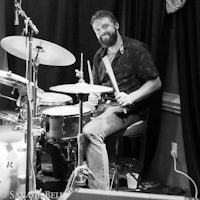 a man with a beard playing drums in a black and white photo