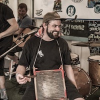 a man with a beard is playing a banjo in front of a group of people