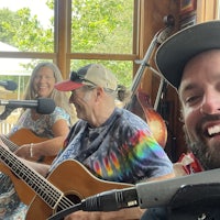 a group of people playing acoustic guitars in front of a microphone